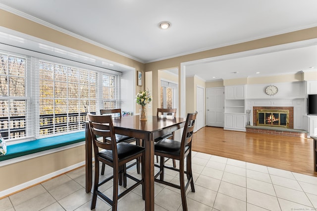 dining room with ornamental molding, light tile patterned floors, built in shelves, and a fireplace