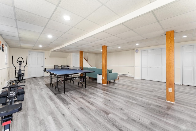 rec room featuring light wood-type flooring, a drop ceiling, and baseboard heating