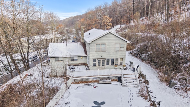 snow covered rear of property with a wooden deck