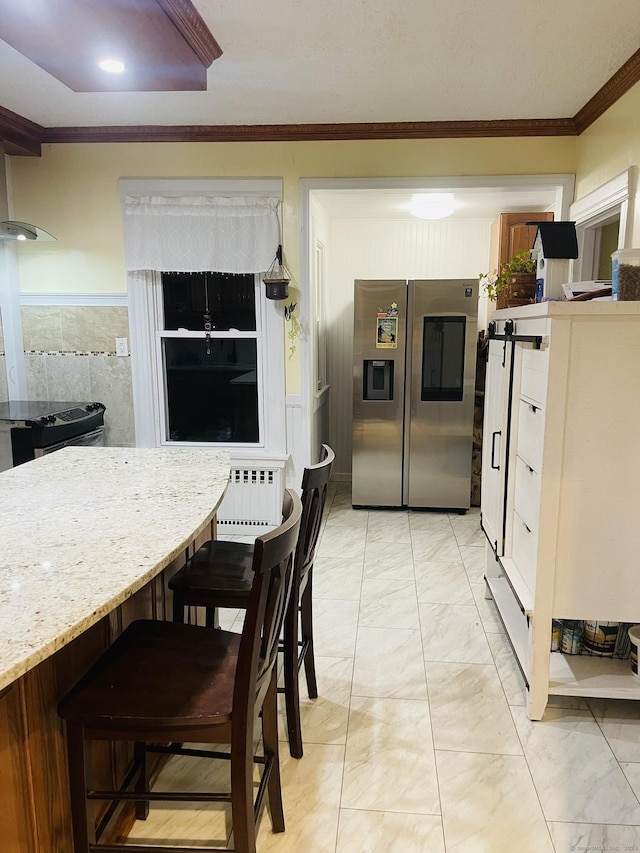 kitchen with a breakfast bar area, stainless steel fridge with ice dispenser, crown molding, and light stone countertops