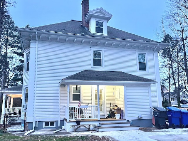 snow covered back of property with covered porch