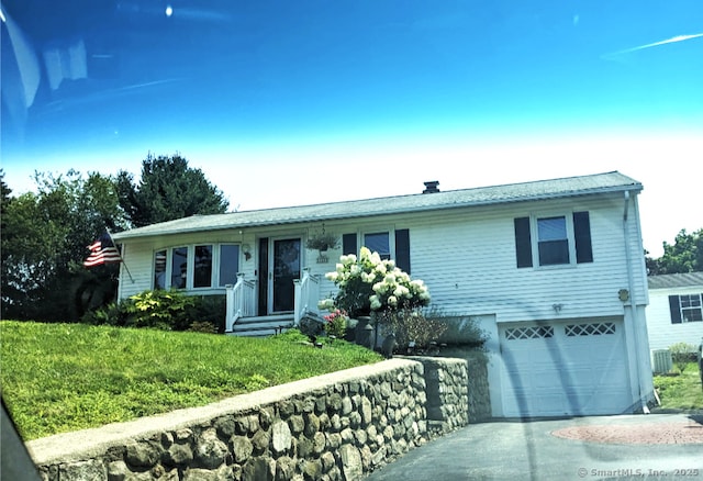 view of front of home with central AC unit, a garage, and a front lawn