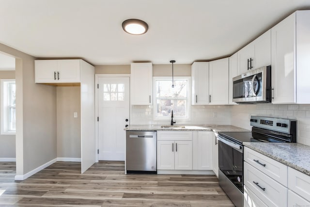 kitchen featuring sink, white cabinetry, stainless steel appliances, and hanging light fixtures