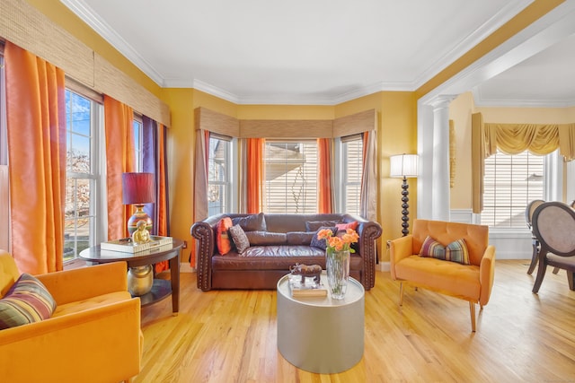 living room featuring light hardwood / wood-style floors, crown molding, and decorative columns