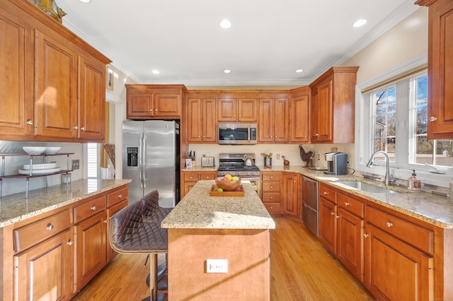 kitchen with light wood-type flooring, stainless steel appliances, sink, a center island, and a breakfast bar area