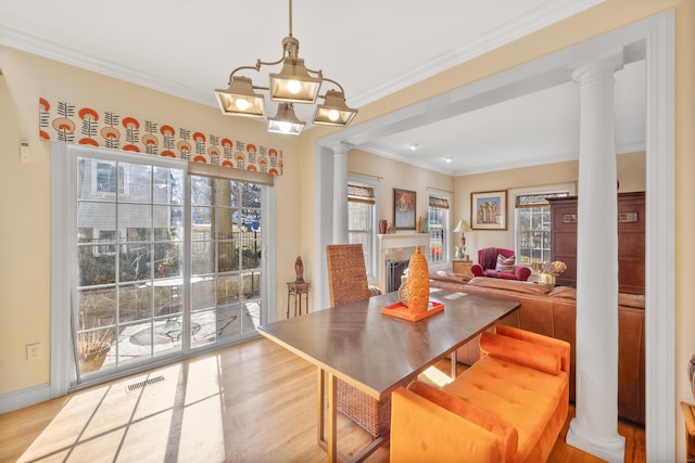 dining room featuring an inviting chandelier, decorative columns, and light hardwood / wood-style flooring