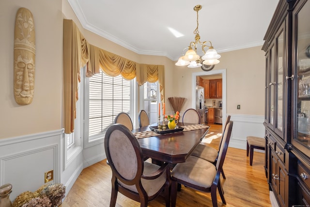 dining area with a chandelier, crown molding, and light hardwood / wood-style floors