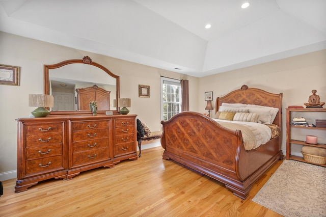 bedroom with a raised ceiling and light wood-type flooring