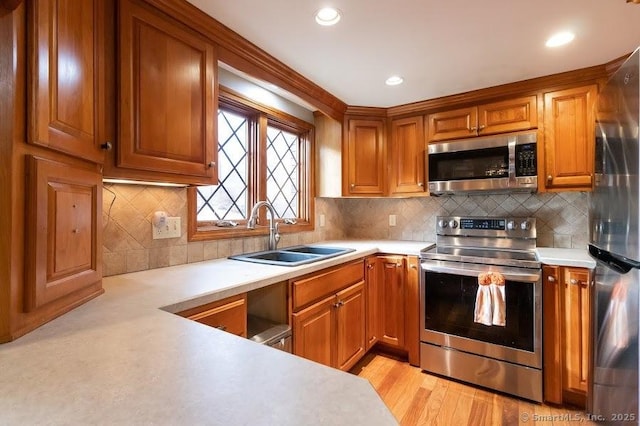 kitchen with sink, decorative backsplash, light hardwood / wood-style flooring, and appliances with stainless steel finishes