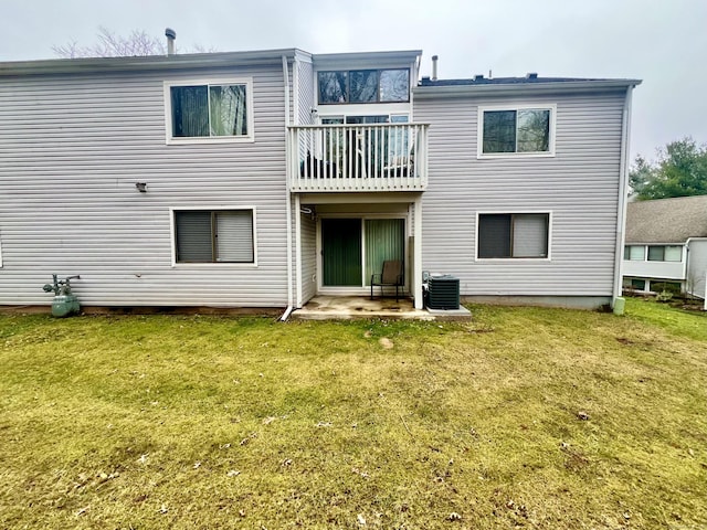 rear view of house with central AC unit, a balcony, and a yard