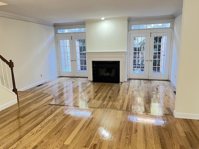 unfurnished living room with french doors, ornamental molding, and light wood-type flooring