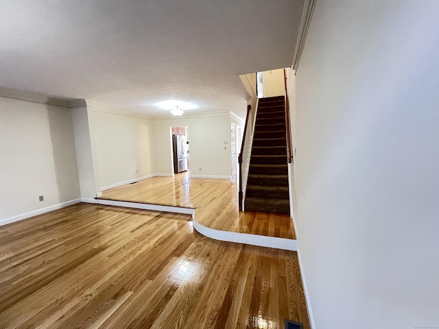 basement with stainless steel fridge, ornamental molding, and hardwood / wood-style flooring