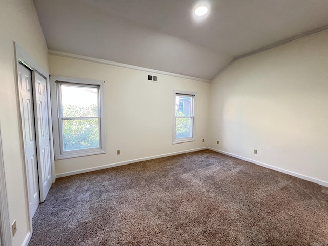 carpeted empty room featuring crown molding and lofted ceiling