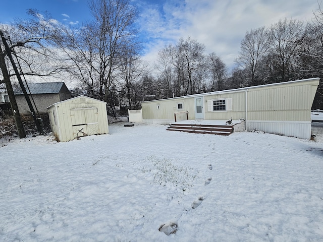 snow covered property featuring a shed and a wooden deck