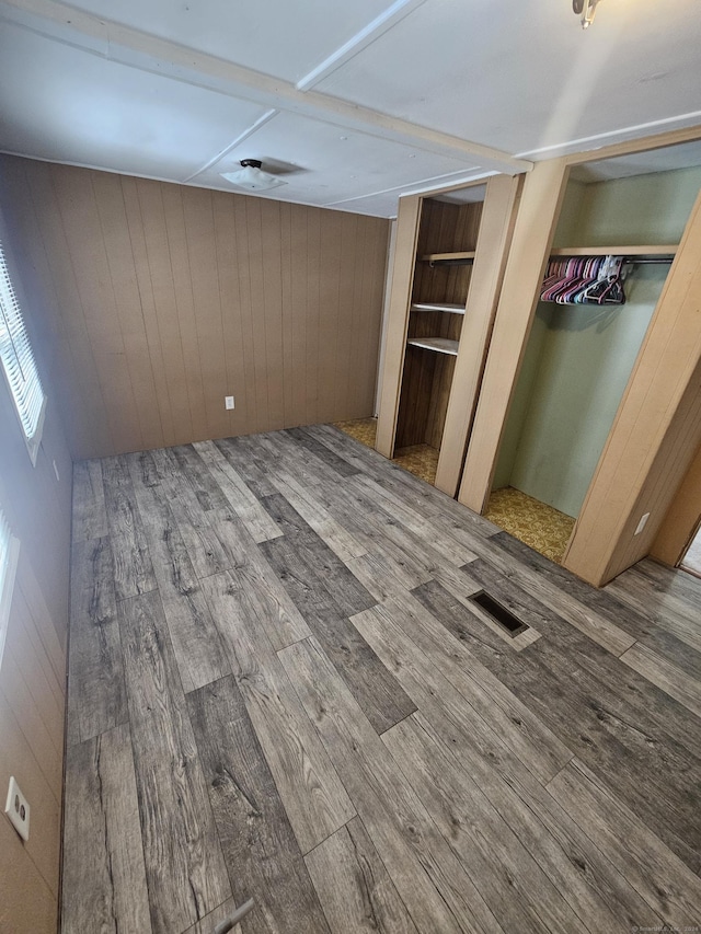 unfurnished bedroom featuring hardwood / wood-style floors and wooden walls