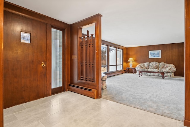 carpeted foyer entrance with wood walls and a baseboard heating unit