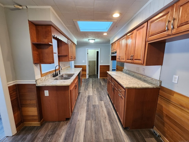 kitchen featuring dark hardwood / wood-style floors, light stone countertops, sink, and a skylight