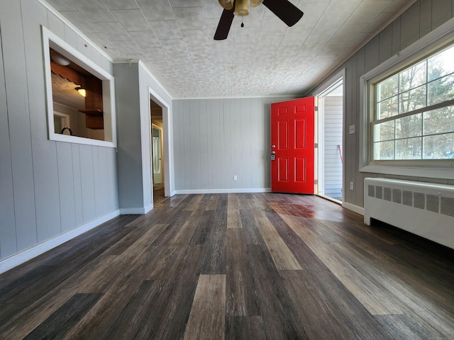 interior space featuring ceiling fan, wood walls, dark hardwood / wood-style flooring, and radiator