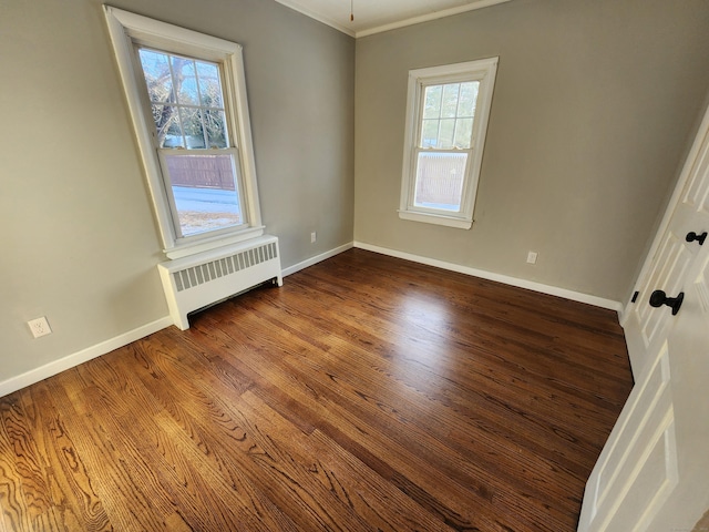 empty room featuring wood-type flooring, radiator, and crown molding