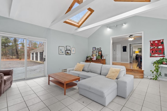 living room featuring beamed ceiling, a skylight, ceiling fan, and light tile patterned flooring