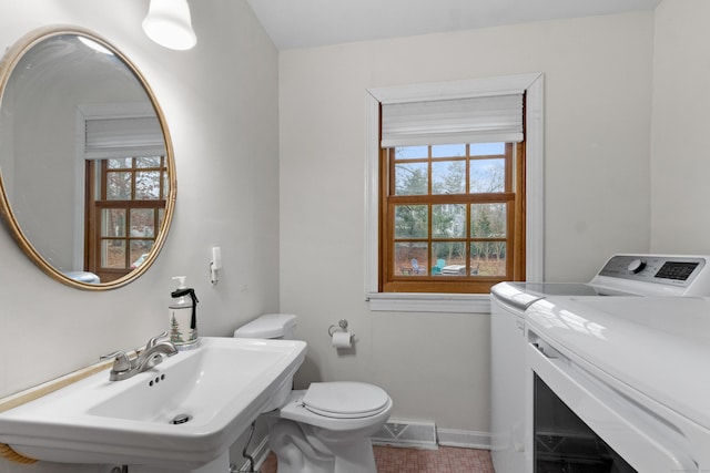 bathroom with washing machine and dryer, sink, tile patterned flooring, and toilet