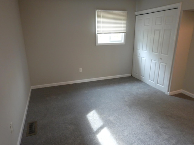 unfurnished bedroom featuring dark carpet and a closet