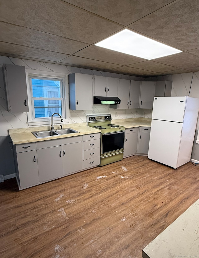 kitchen with range with electric cooktop, tasteful backsplash, sink, white refrigerator, and light wood-type flooring