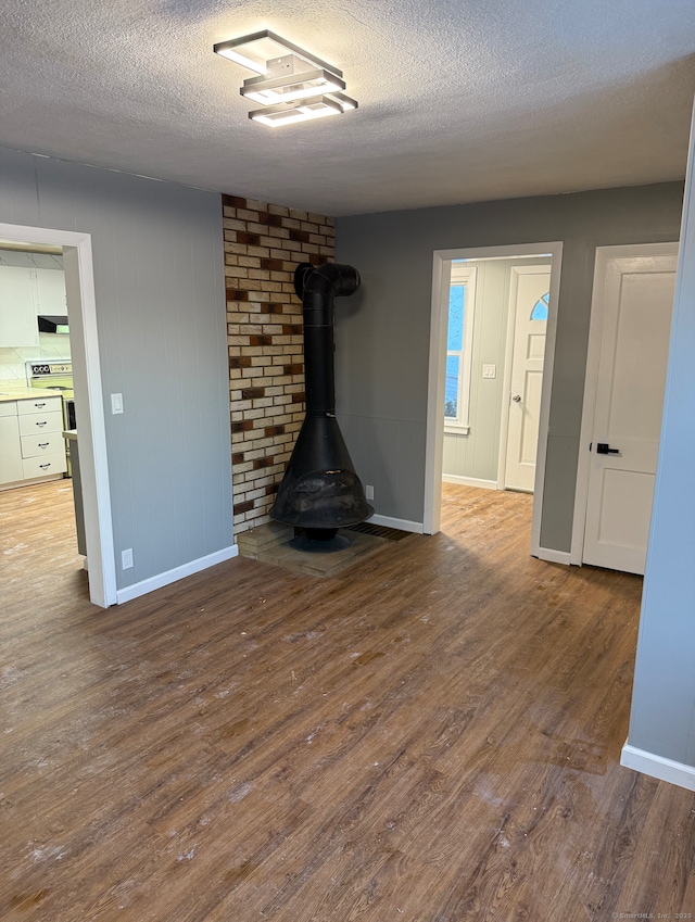 unfurnished living room with hardwood / wood-style floors, a textured ceiling, and a wood stove