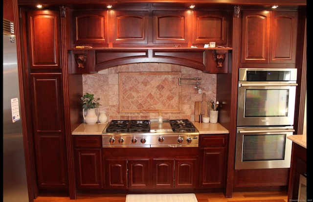 kitchen with backsplash, range hood, and appliances with stainless steel finishes