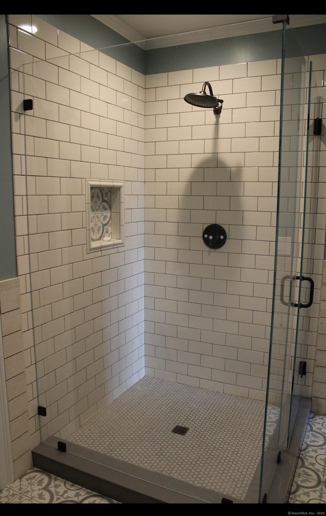 bathroom with crown molding and a shower with shower door