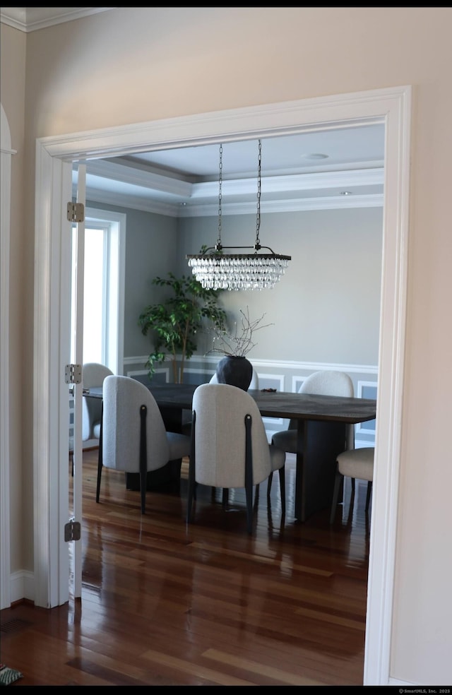 dining area featuring dark hardwood / wood-style flooring, crown molding, and a tray ceiling