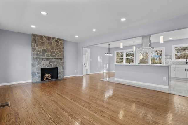 unfurnished living room featuring a stone fireplace, light hardwood / wood-style flooring, and a healthy amount of sunlight