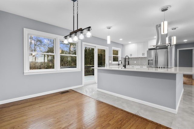 kitchen with pendant lighting, decorative backsplash, white cabinetry, and stainless steel fridge with ice dispenser