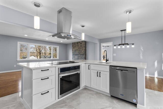 kitchen with stainless steel appliances, island range hood, sink, pendant lighting, and white cabinetry