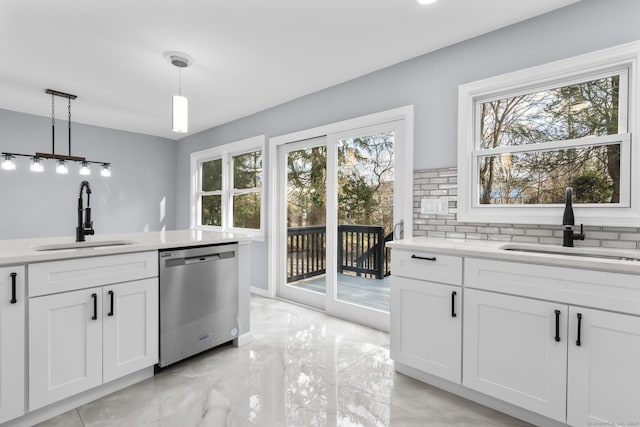 kitchen featuring hanging light fixtures, a wealth of natural light, sink, and stainless steel dishwasher