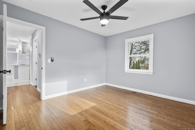 empty room with hardwood / wood-style floors and ceiling fan