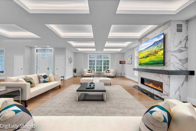 living room with beamed ceiling, light wood-type flooring, a fireplace, and coffered ceiling