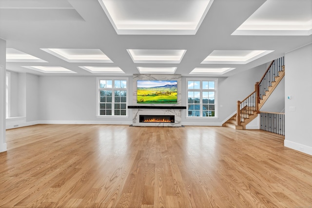 unfurnished living room with light hardwood / wood-style floors, plenty of natural light, and coffered ceiling