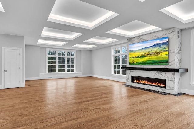 unfurnished living room featuring hardwood / wood-style floors, a premium fireplace, a wealth of natural light, and coffered ceiling