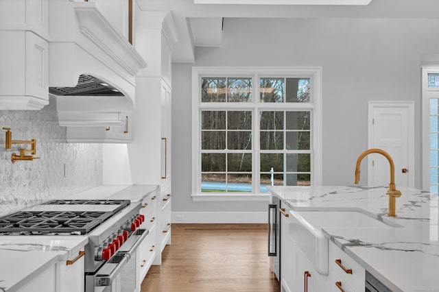 kitchen featuring stainless steel range, decorative backsplash, light stone counters, and a wealth of natural light