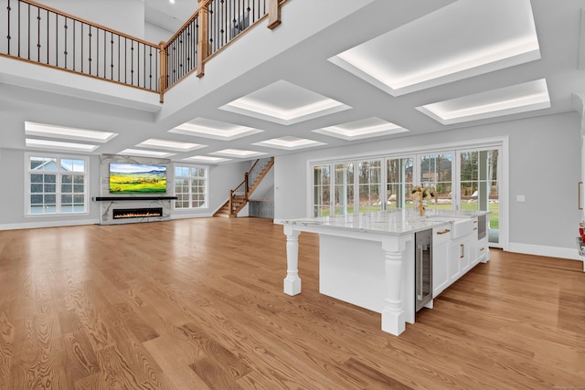 unfurnished living room featuring a fireplace, light wood-type flooring, wine cooler, and a healthy amount of sunlight