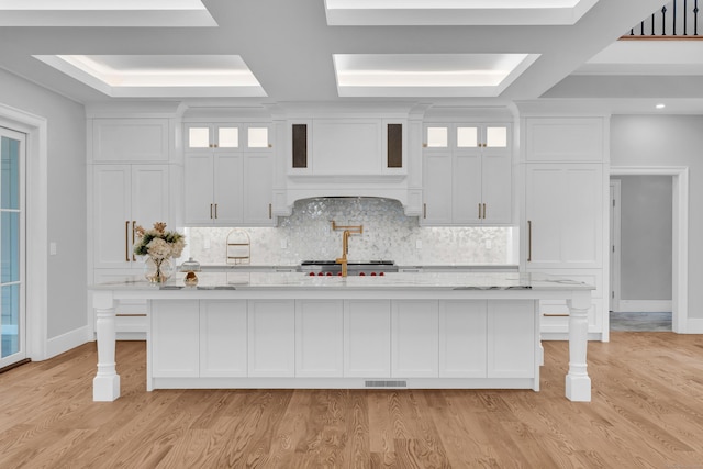 kitchen with a kitchen bar, light hardwood / wood-style floors, white cabinetry, and an island with sink