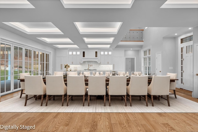 dining area with coffered ceiling, beamed ceiling, and light hardwood / wood-style flooring