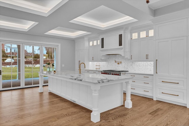 kitchen featuring a kitchen bar, light hardwood / wood-style flooring, white cabinetry, and a kitchen island with sink