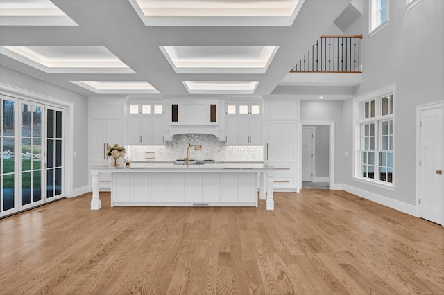 unfurnished living room featuring beamed ceiling, light hardwood / wood-style floors, sink, and coffered ceiling