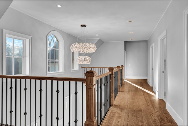 corridor with wood-type flooring and an inviting chandelier