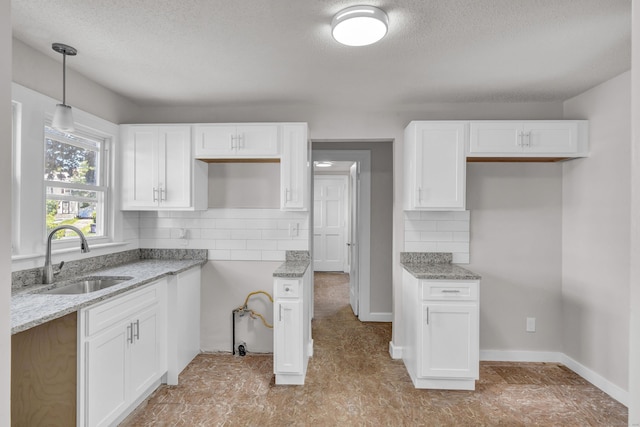 kitchen featuring white cabinetry, sink, and decorative light fixtures