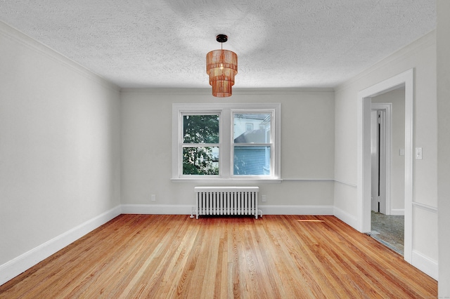 empty room featuring radiator, wood-type flooring, a textured ceiling, and ornamental molding