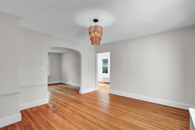 empty room featuring hardwood / wood-style floors, a textured ceiling, radiator, and crown molding