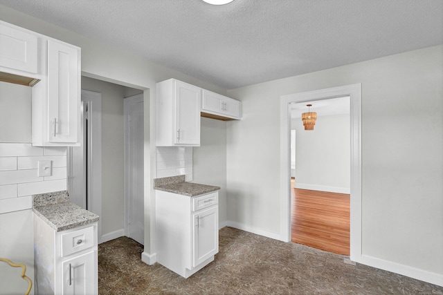 kitchen with decorative backsplash, white cabinetry, a textured ceiling, and stone counters